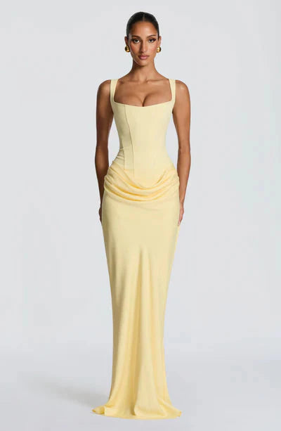 Full-length front view of a pale yellow Celeste Corset Maxi Dress, featuring a structured corset and draped skirt.