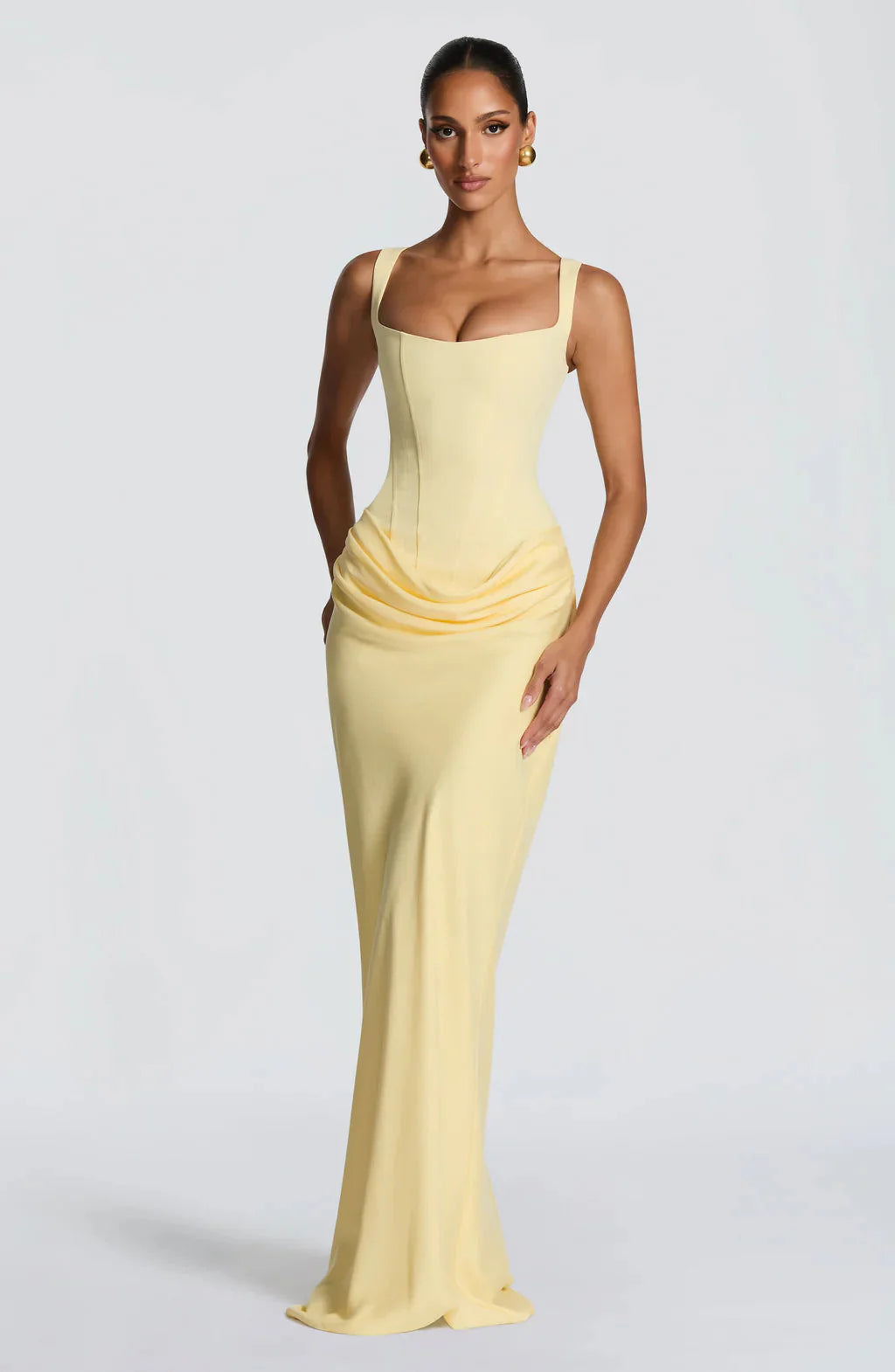 Front view of a light yellow Celeste corset maxi dress with a square neckline and draped skirt detail.