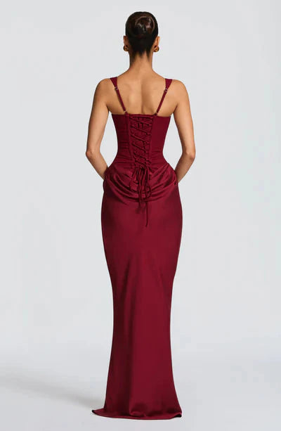 Back view of a rich burgundy Celeste corset maxi dress featuring a full lace-up corset and draped skirt.