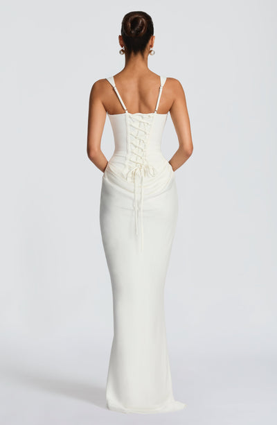 Back view of the ivory Celeste Corset Maxi Dress, displaying the adjustable lace-up corset and flowing skirt.