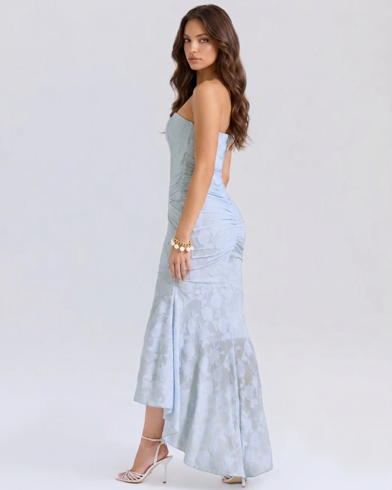 Side view of light blue corset midi dress with fitted ruched skirt and floral jacquard high-low hem