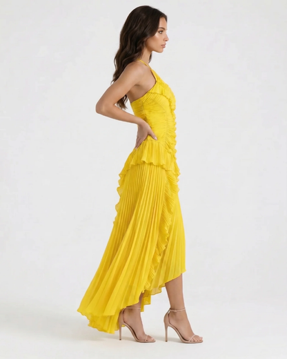 Profile view of yellow pleated maxi dress with cascading ruffles down front and flowing asymmetrical skirt