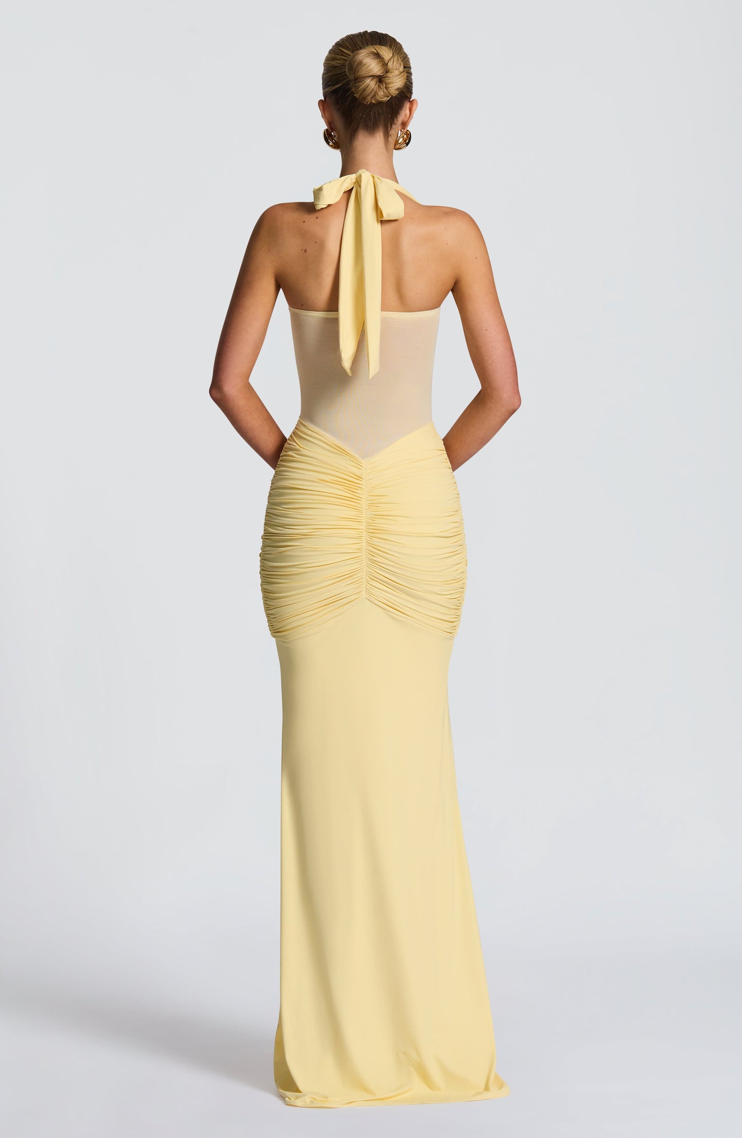 Back view of the light yellow Jayleen Ruched Maxi Dress, featuring a tie-back halter and ruched detailing.
