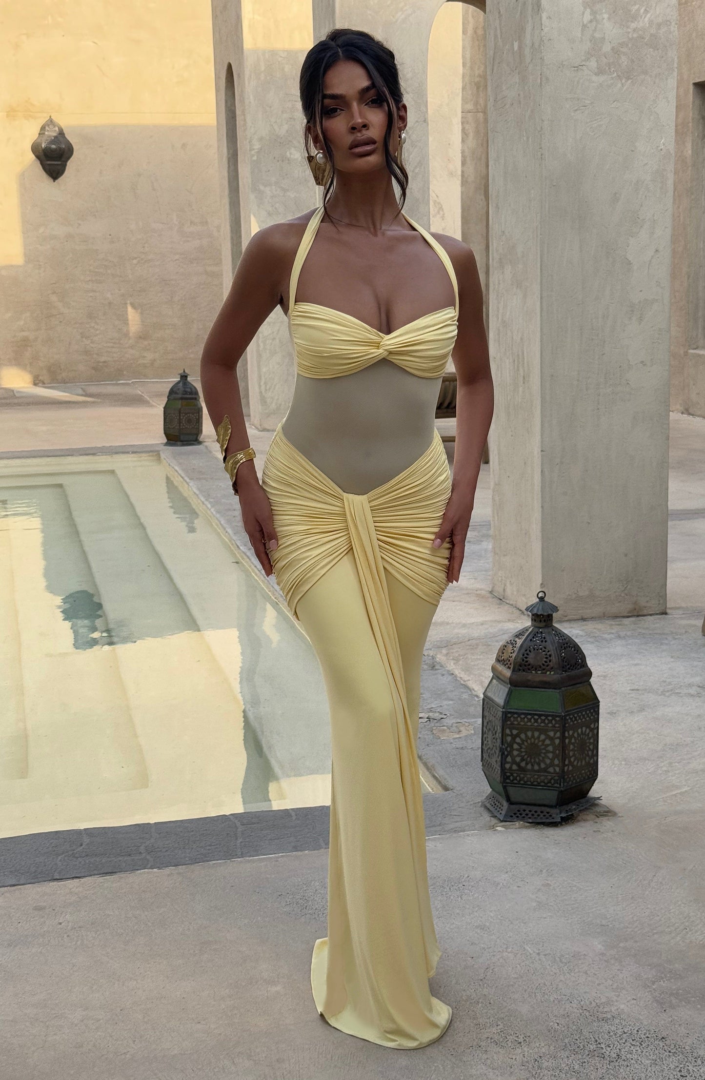 Yellow halter neck maxi dress with ruched details and sheer midriff, perfect for a special occasion.