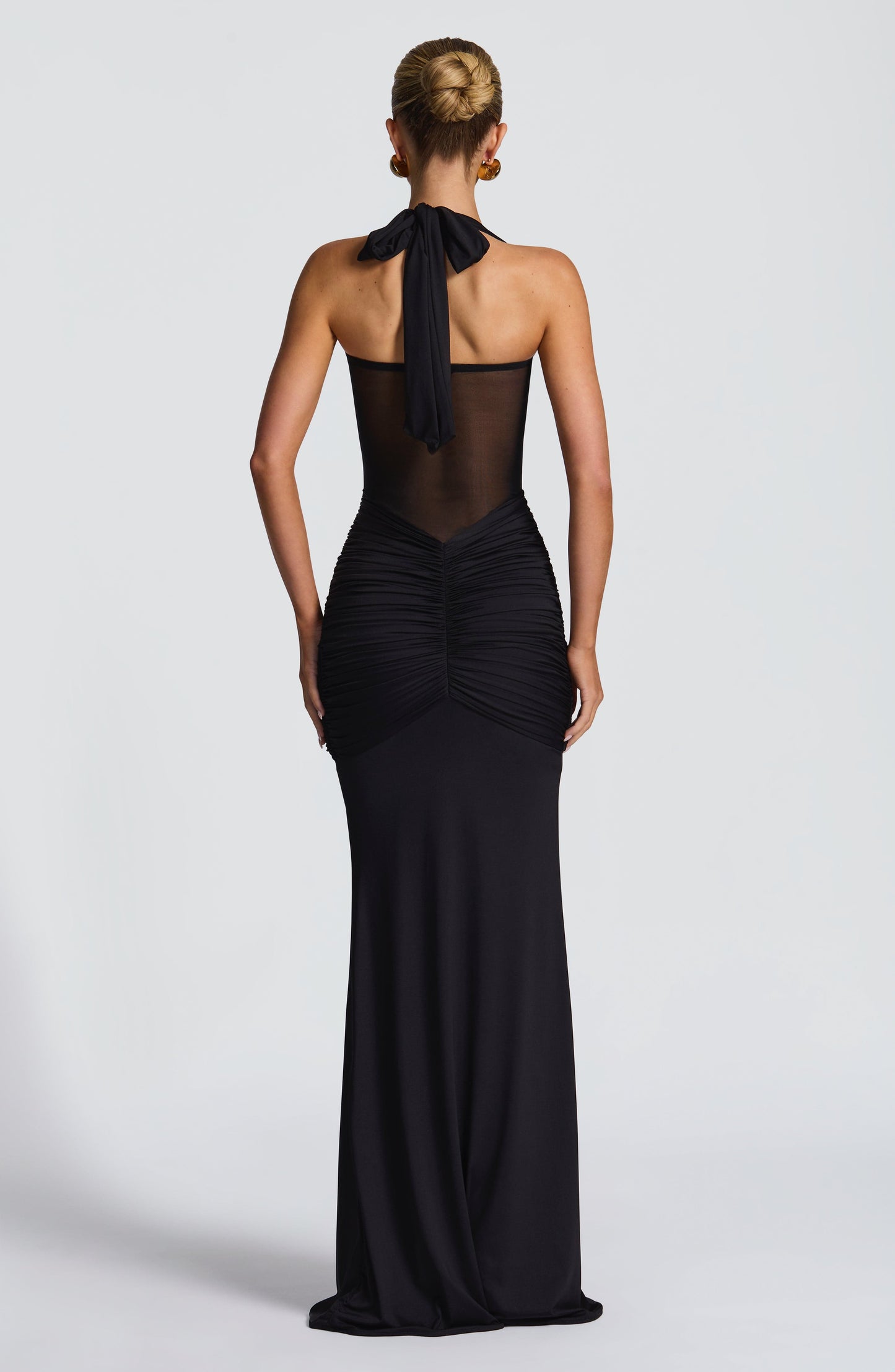 Back view of the black Jayleen Ruched Maxi Dress, showing the tie-back halter and ruched lower back.