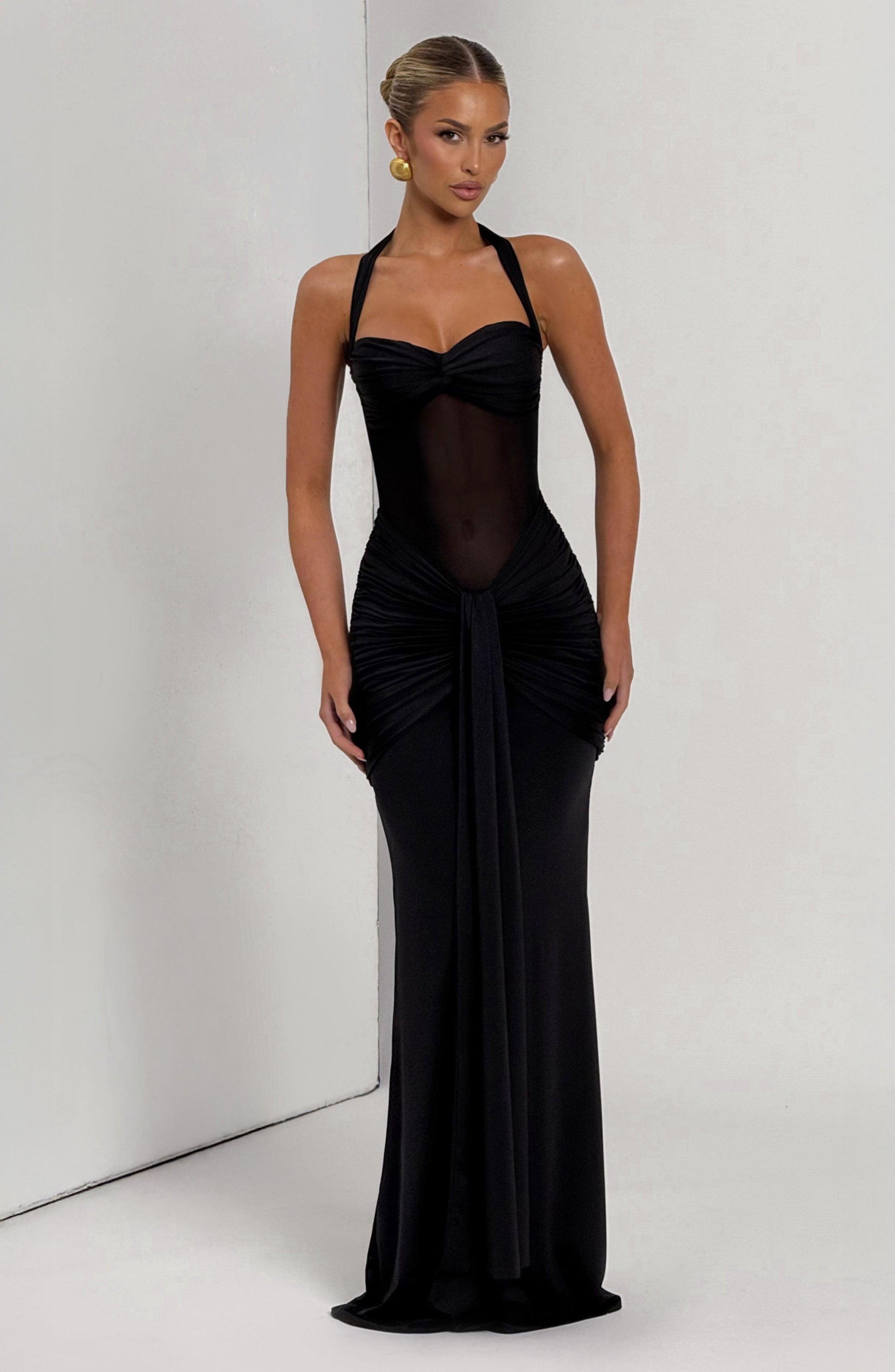 Full body shot of the black Jayleen Ruched Maxi Dress with a sheer midriff and elegant draping.