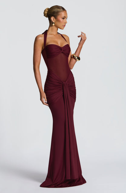 Side profile of the elegant deep red Jayleen Ruched Maxi Dress with a halter neck and draped skirt.