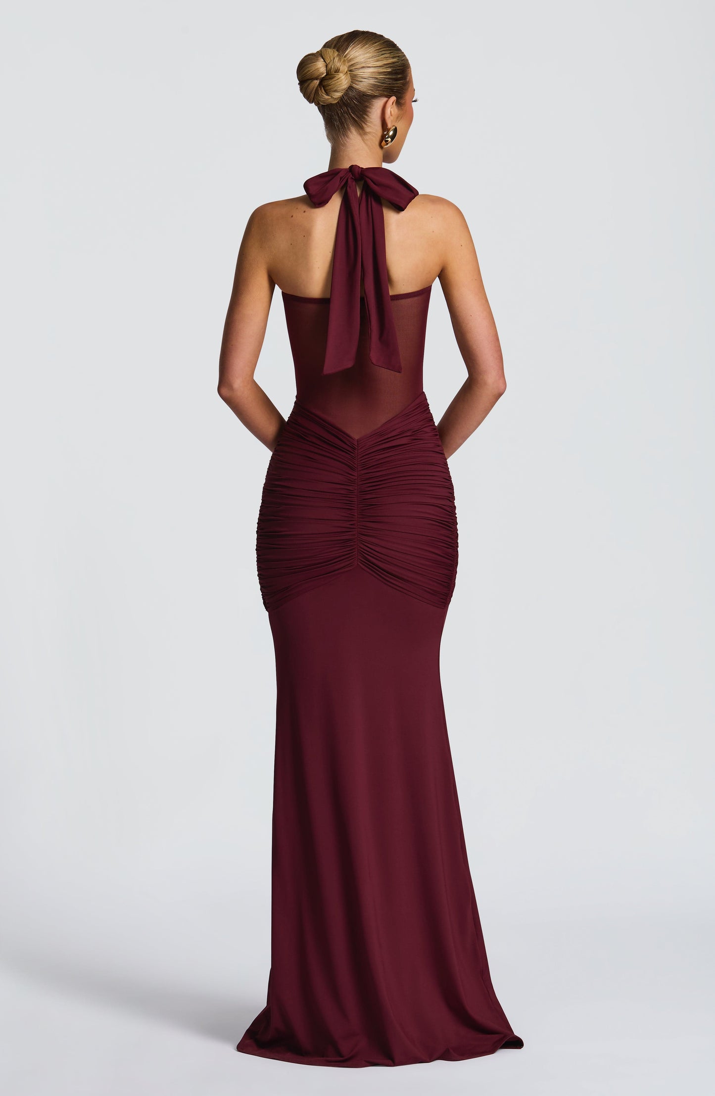 Back view of the deep red Jayleen Ruched Maxi Dress, featuring a tie-back halter and ruched detailing.