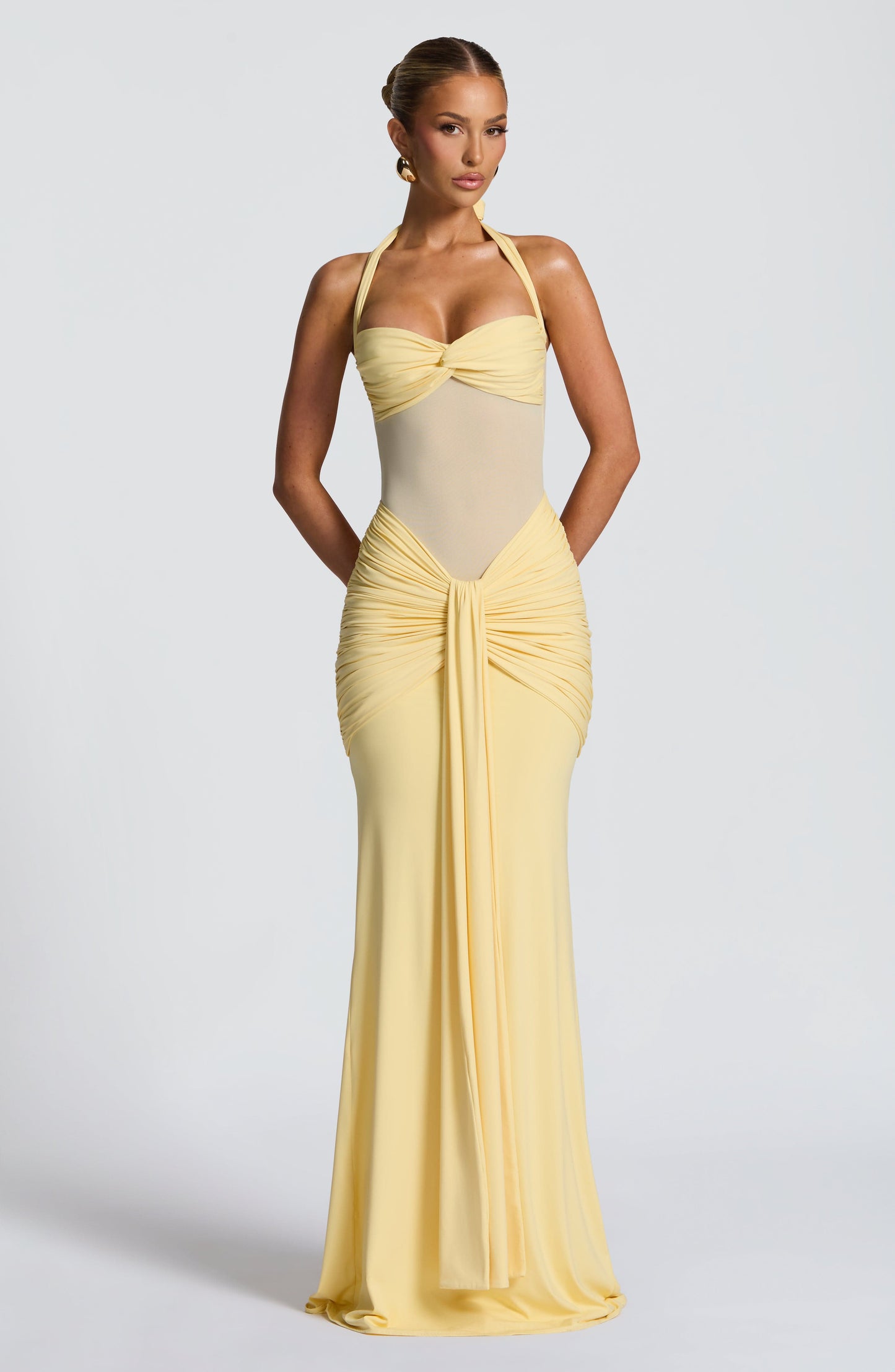 Full length view of a light yellow Jayleen Ruched Maxi Dress with a halter neckline and front knot detail.