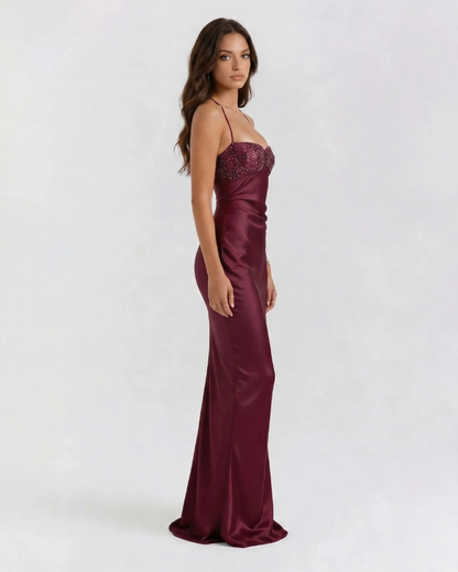 Side view of burgundy sequin maxi dress with fitted satin silhouette and floor-length hem