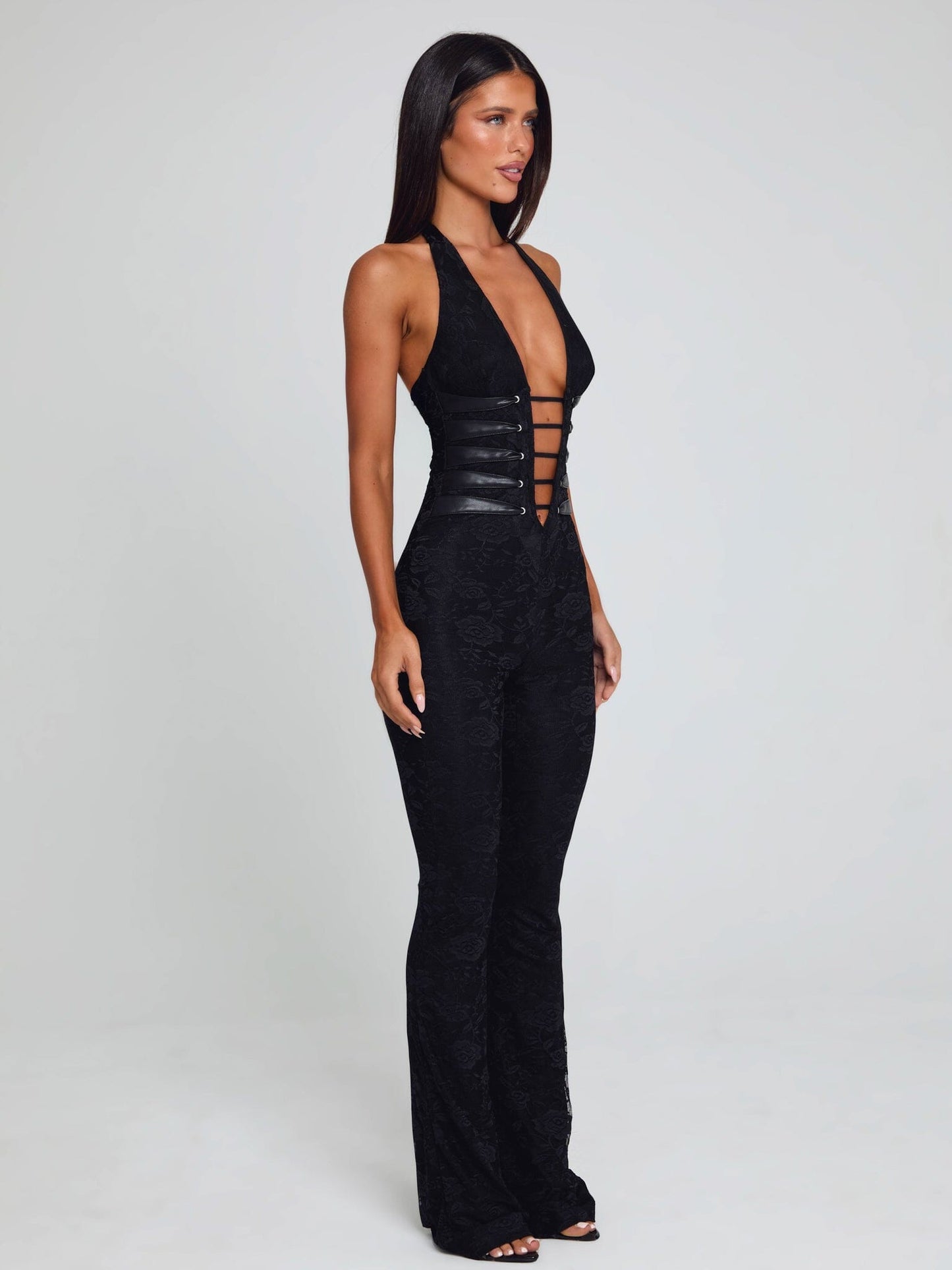 Side view of the black Kenzie halter jumpsuit, highlighting the deep V-neck, detailed corset lacing, and the elegant silhouette.
