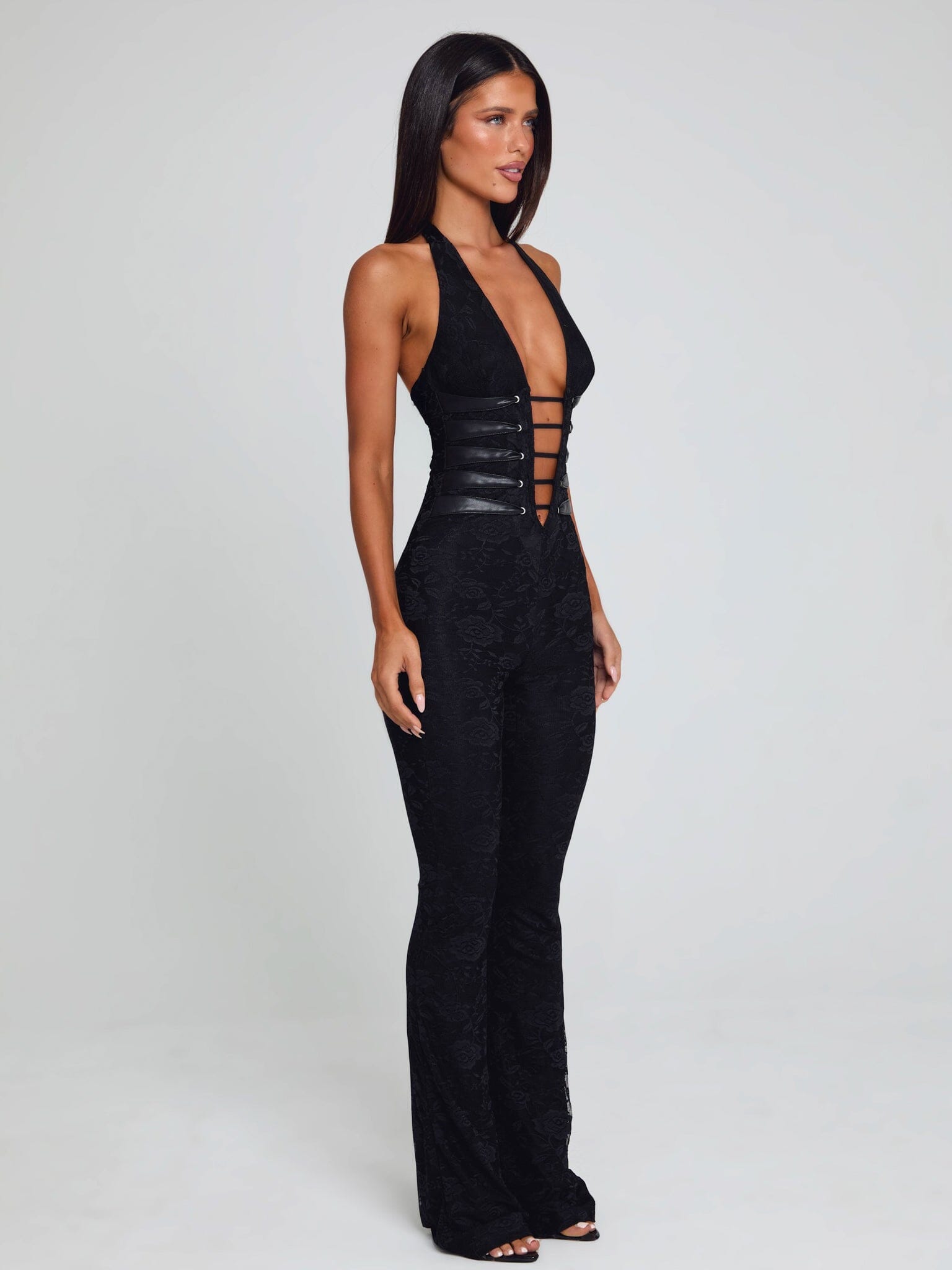 Side view of the black Kenzie halter jumpsuit, highlighting the deep V-neck, detailed corset lacing, and the elegant silhouette.