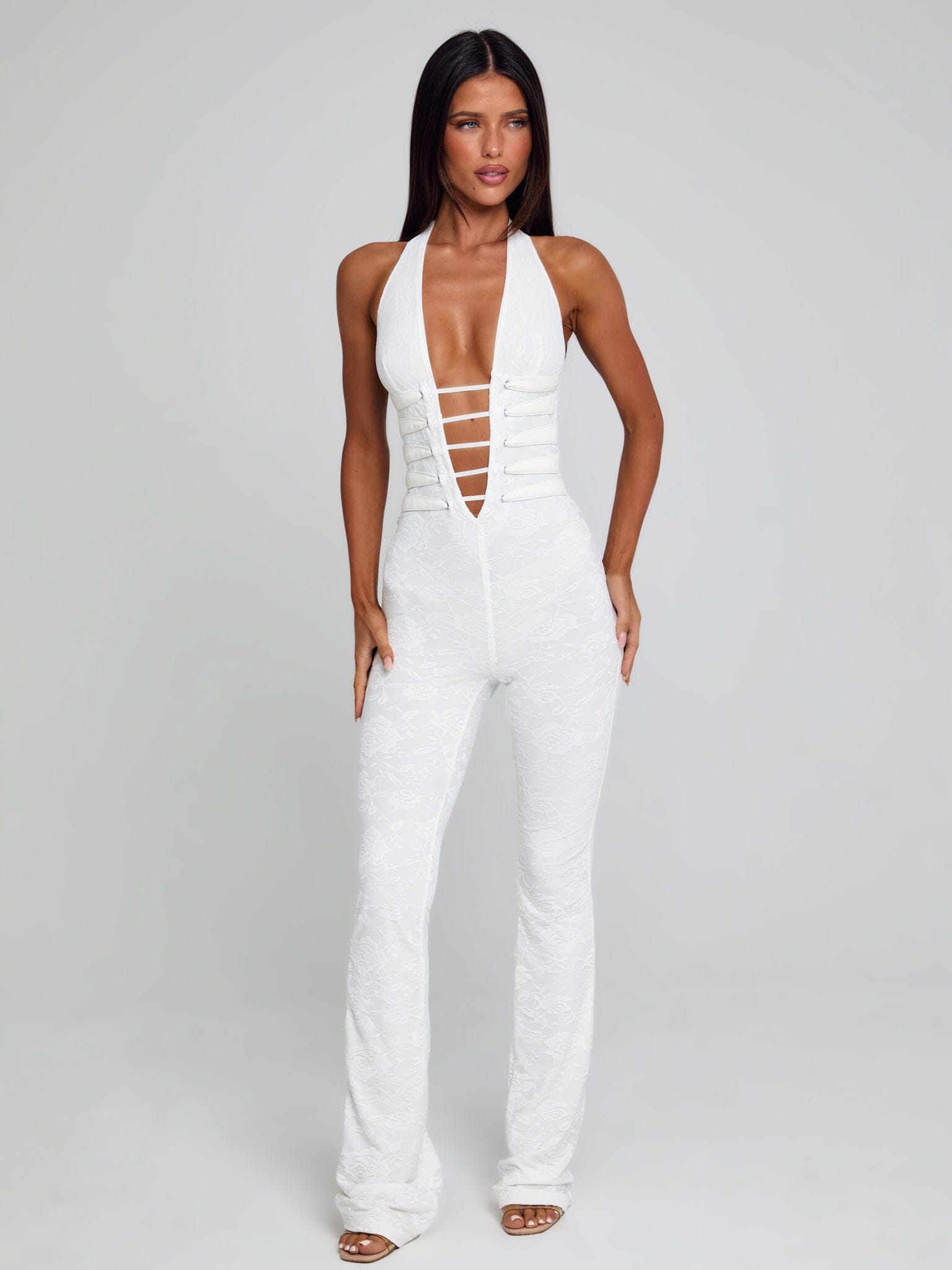 Full body shot of a white Kenzie Halter Jumpsuit, featuring a halter neckline, deep V, and flared pant legs.