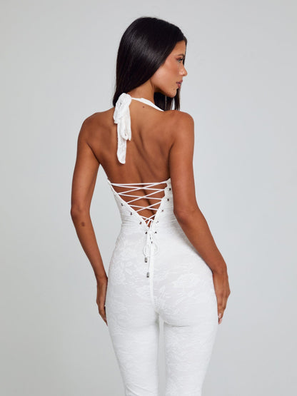 Angled rear view of a white Kenzie Halter Jumpsuit, showing the halter neck tie and intricate back lacing.