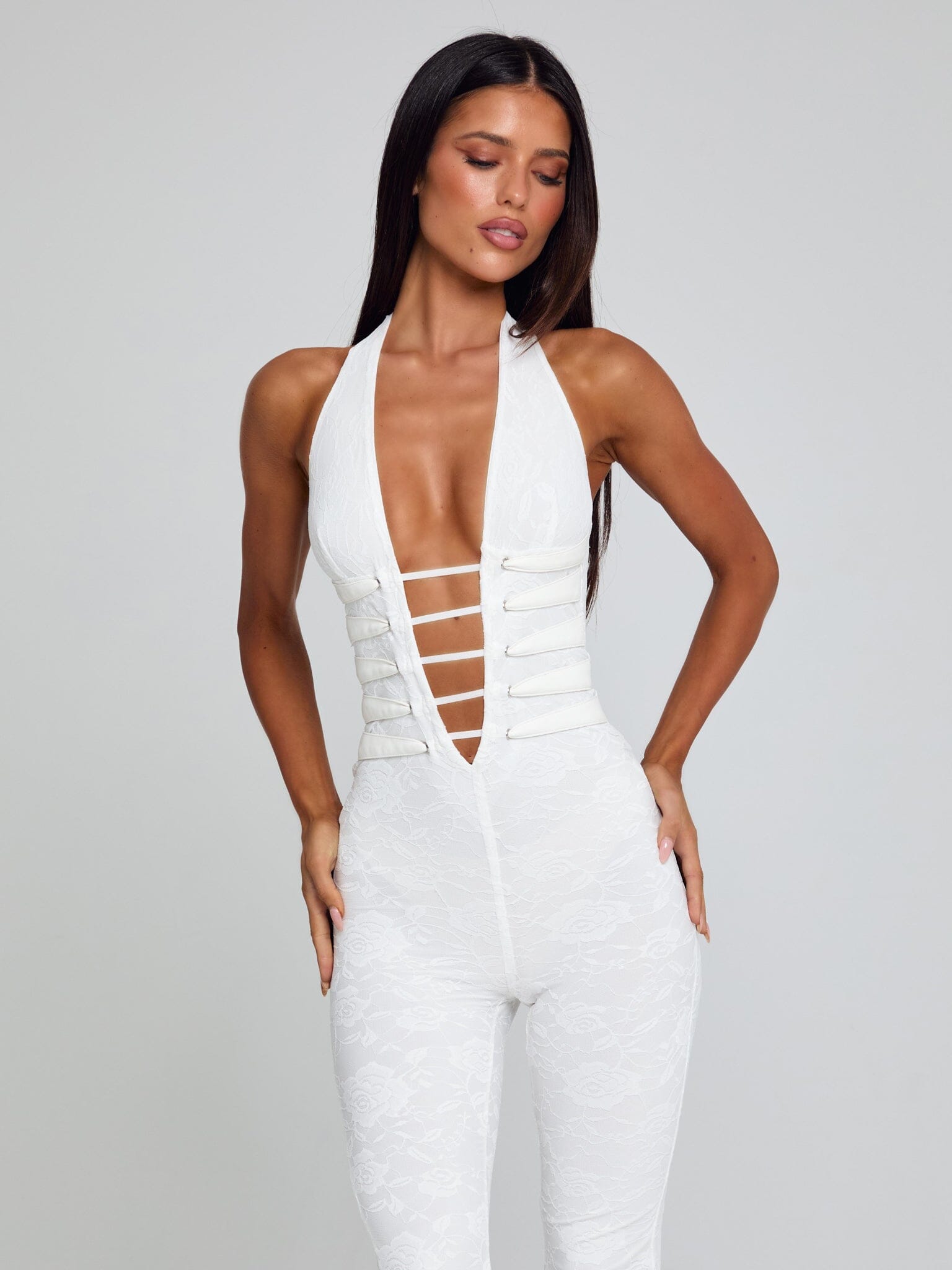 Frontal view of a white Kenzie Halter Jumpsuit, with a deep plunge neckline and white horizontal straps across the midriff.