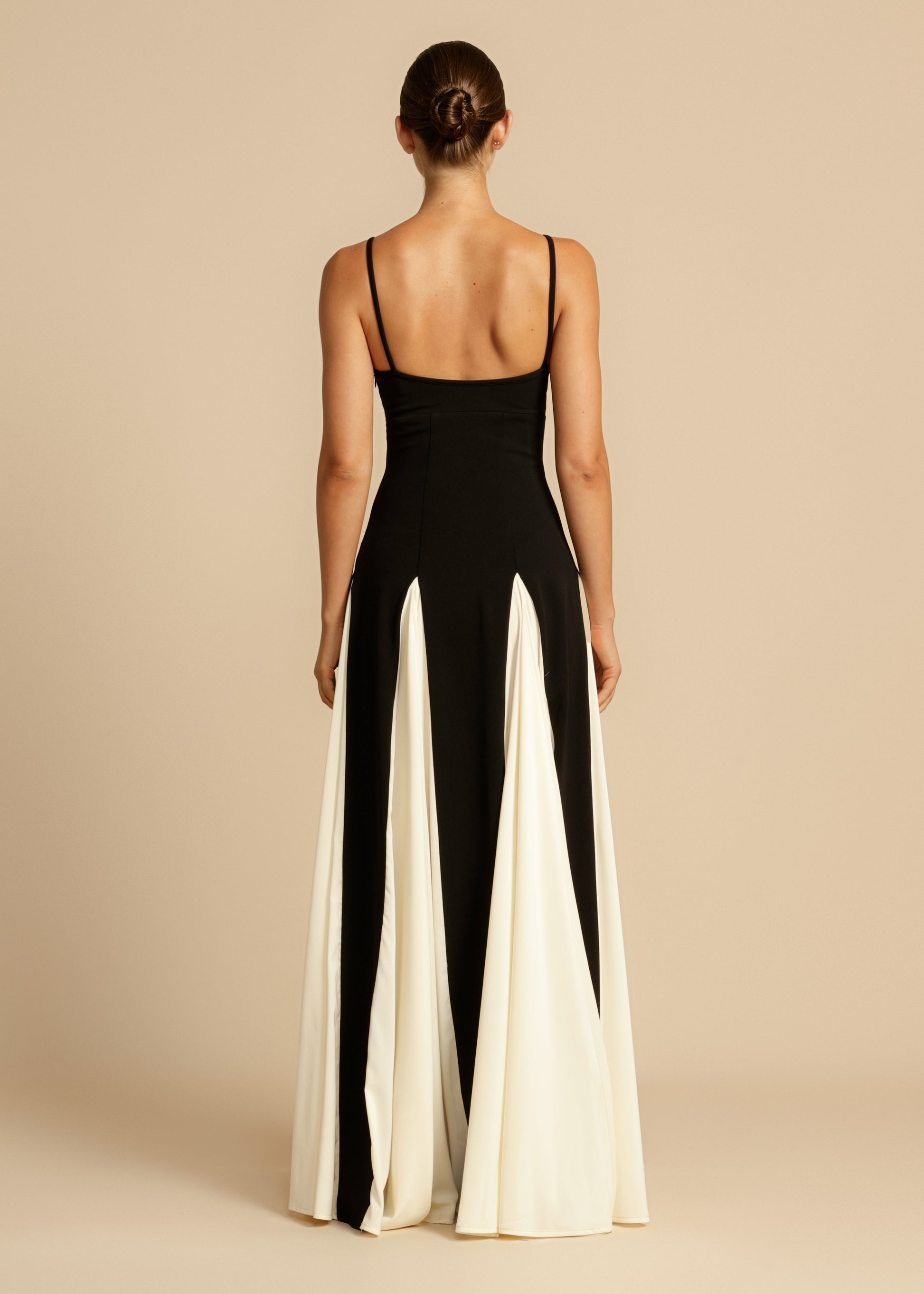 Rear view of a black and white paneled maxi dress, showcasing the full skirt and thin shoulder straps.