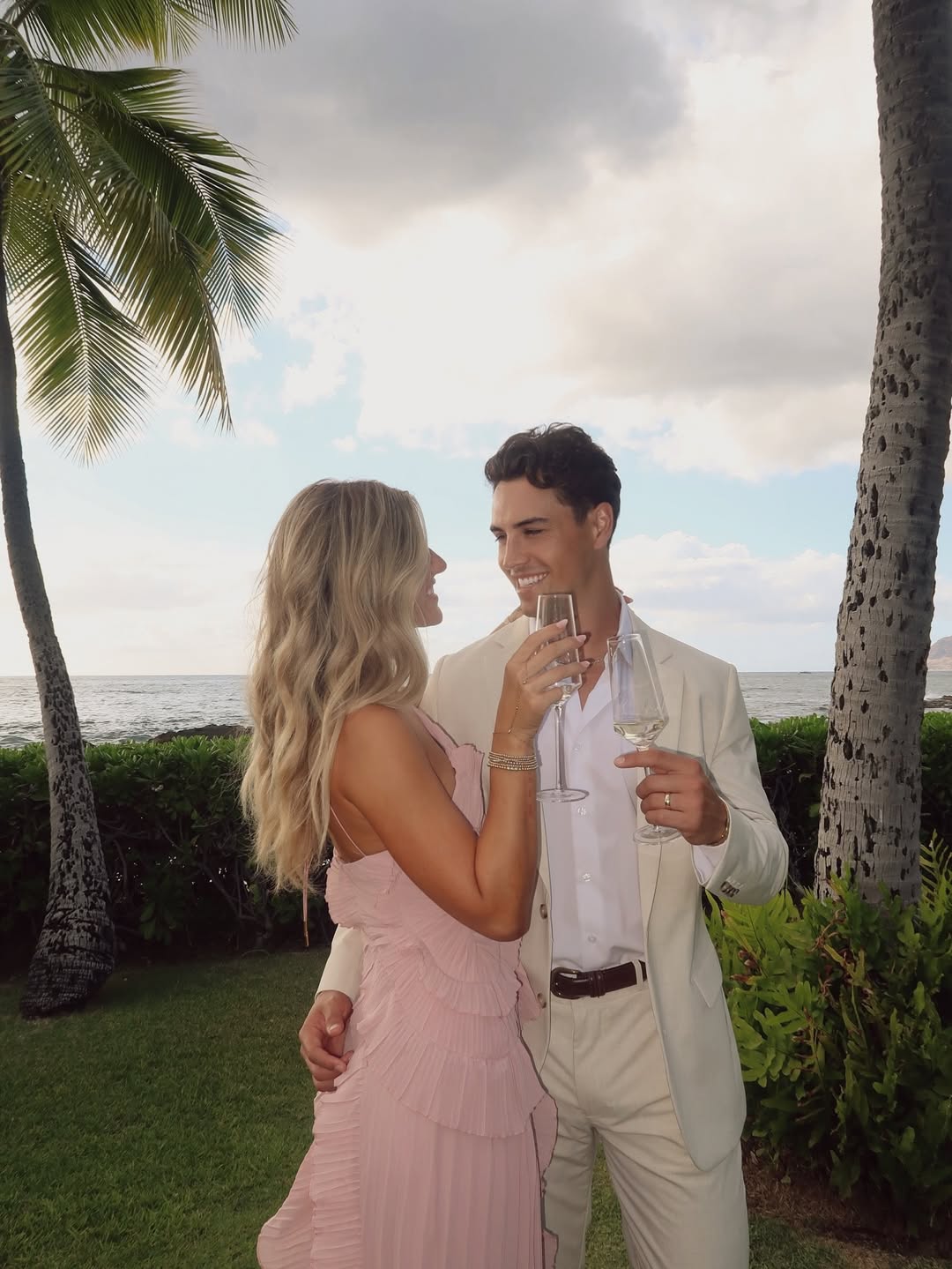 Couple enjoying drinks outdoors, woman in the pink Millie Ruffle Midi Dress with a pleated skirt.