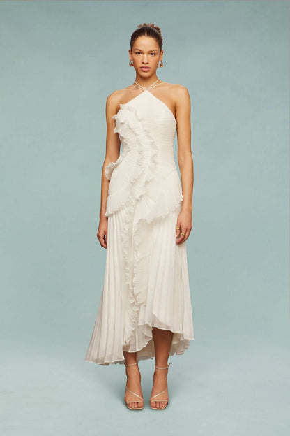 Model standing in a white Millie Ruffle Midi Dress, featuring a pleated skirt and distinctive ruffled design.