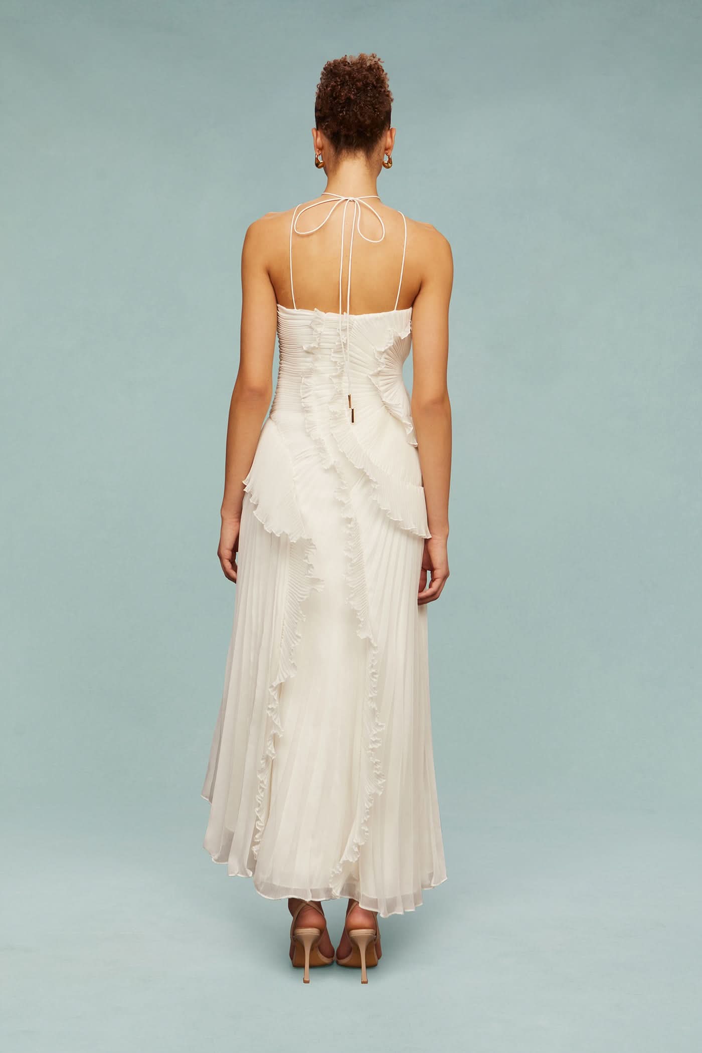 Back view of a white Millie Ruffle Midi Dress featuring a pleated skirt and ruffled detailing, tied with delicate straps.