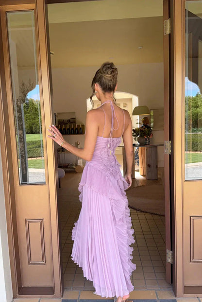 Back view of the lavender Millie Ruffle Midi Dress showing the thin halter straps and intricate pleating details, as a woman walks away.