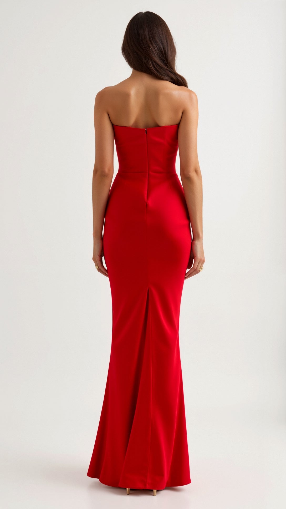 Back view of a woman in a vibrant red strapless maxi dress, highlighting the form-fitting design and discreet back zipper closure.