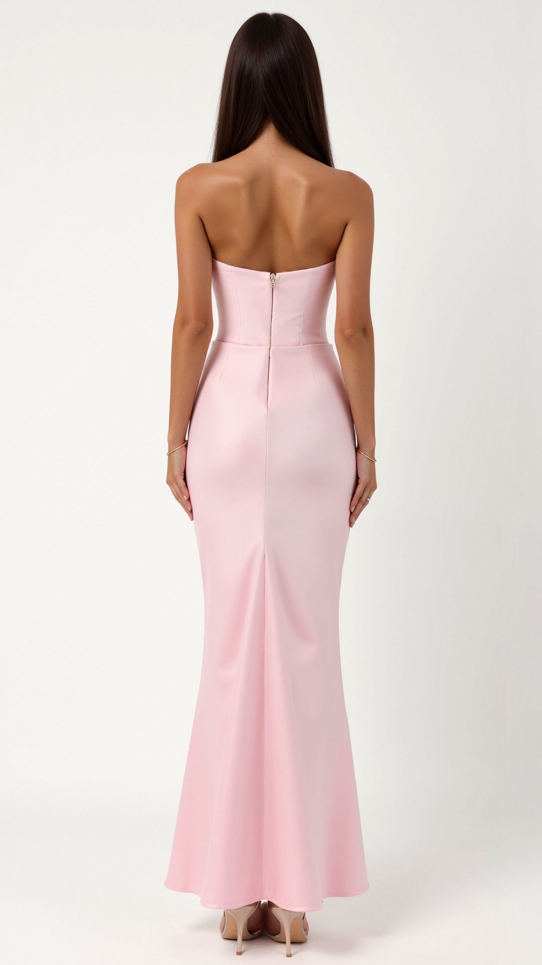 Back view of a woman in a light pink strapless maxi dress, featuring a clean back design with a hidden zipper and a modest slit.