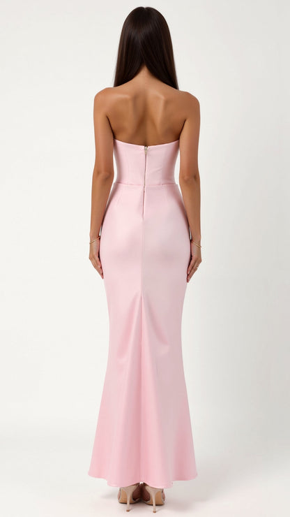 Back view of a woman in a light pink strapless maxi dress, featuring a clean back design with a hidden zipper and a modest slit.