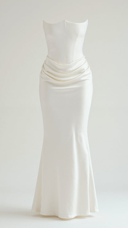 Elegant white strapless maxi dress with a structured bodice and draped waist detail, flowing into a slim skirt.