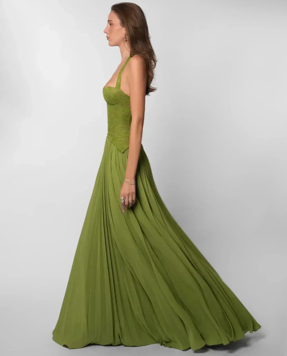 Model walking in green lace maxi dress with flowing pleated skirt and halter top for women.